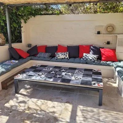 a blue couch with red pillows on a patio at Maison de charme à Aix-en-Provence in Aix-en-Provence