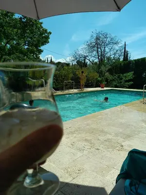 a glass of wine sitting next to a swimming pool at Maison de charme à Aix-en-Provence in Aix-en-Provence