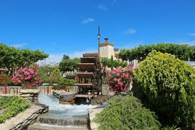 a waterfall in a garden with flowers and trees at Grand appartement spacieux et lumineux à Noves in Noves