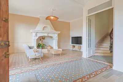 a living room with a fireplace and a chair and a tv at Le Champ des Cigales in Noves