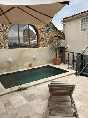 a swimming pool with two chairs and an umbrella at Maison de village en Provence Luberon in Saint-Saturnin-les-Apt