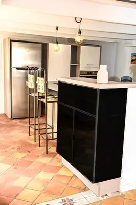 a kitchen with a black counter and a refrigerator at Maison provençale avec piscine et vue in Viens