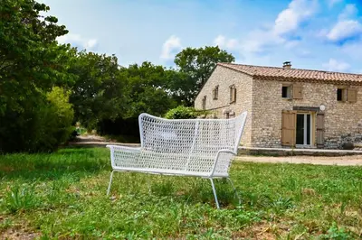 a white bench sitting in the grass in front of a building at Maison provençale avec piscine et vue in Viens