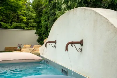 a swimming pool with a water hose attached to a wall at La Maison PP une Parenthèse Provençale in Carpentras