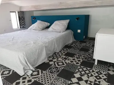 a bedroom with a blue bed with a black and white floor at Nid douillet au cœur du Vaucluse in Entraigues-sur-la-Sorgue