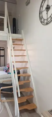 a staircase in a room with a bed and a clock at Nid douillet au cœur du Vaucluse in Entraigues-sur-la-Sorgue