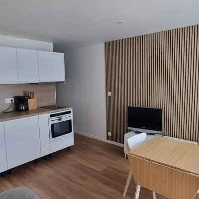 a kitchen with white cabinets and a table and a table and a television at Appartement in Aix-en-Provence
