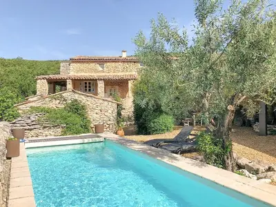 a swimming pool in front of a stone house at Hameau de l'Esperelle in Simiane-la-Rotonde