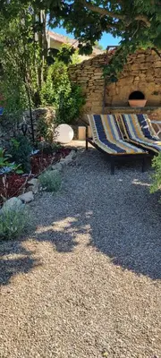 a bench in a garden with a stone wall at La BERGERIE in Pélissanne