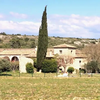 a large building with a tree in a field at La BERGERIE in Pélissanne