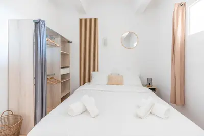 a white bedroom with two beds and a closet at Appartement spacieux, chaleureux & tout confort in Pertuis
