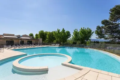 a large swimming pool with chairs around it at Superbe appartement dans golf 4 étoiles in Saumane-de-Vaucluse
