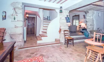 a living room with a stone fireplace and a staircase at Authentique Bergerie Coeur Luberon in Lacoste