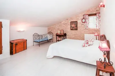 a bedroom with a white bed and a brick wall at Authentique Bergerie Coeur Luberon in Lacoste