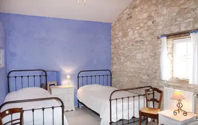 a bedroom with two beds and a stone wall at Authentique Bergerie Coeur Luberon in Lacoste