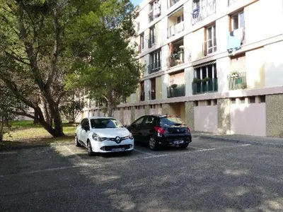 two cars parked in a parking lot next to a building at Agréable appartement Montfavet Avignon in Avignon
