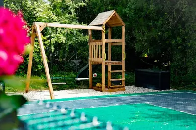 a wooden playground with a wooden ladder next to a tennis court at La Maison PP - Appartements in Carpentras
