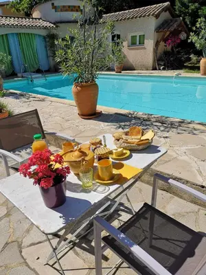 a table with food on it next to a pool at Chambre d'hôte à Pierrevert, en Haute Provence in Pierrevert
