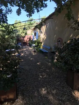 a pathway with benches in a yard next to a building at Le Bois De La Cour in Roussillon