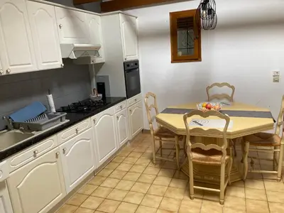 a kitchen with white cabinets and a table with chairs at Les Vignes in Maubec