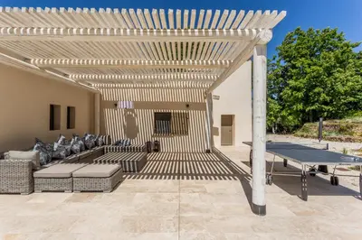 a wooden pergola with a ping pong table on a patio at Villa Kiki 4 chambres Climatisée Ménerbes in Ménerbes