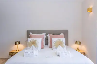 a bedroom with a white bed with pink pillows at Villa Kiki 4 chambres Climatisée Ménerbes in Ménerbes