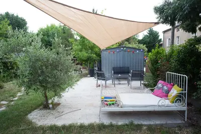 a patio with a bed under a mosquito net at Maison dans un coin de verdure proche de la Sorgue in LʼIsle-sur-la-Sorgue