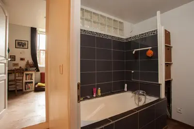 a bath tub in a bathroom with black tiles at Maison dans un coin de verdure proche de la Sorgue in LʼIsle-sur-la-Sorgue