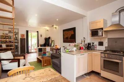 a kitchen and living room with a couch and a table at Maison dans un coin de verdure proche de la Sorgue in LʼIsle-sur-la-Sorgue