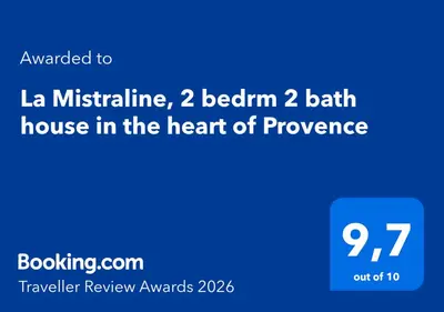 a stone building with a wooden door and a balcony at La Mistraline, in the center of the Luberon, Provence 2 bedroom, 2 bath Village House in Caseneuve