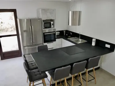 a kitchen with a black counter top and a refrigerator at Les Calanques - Mas des Sous-Bois in Ventabren