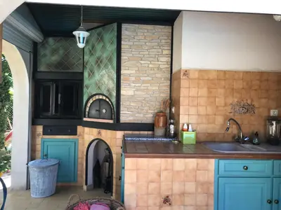 an outdoor kitchen with a sink and a oven at Joli rez de villa proche d'Aix-en-Provence in Peyrolles-en-Provence
