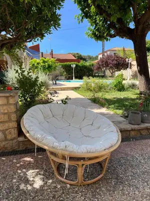 a rattan bed sitting on the ground next to a tree at Joli rez de villa proche d'Aix-en-Provence in Peyrolles-en-Provence