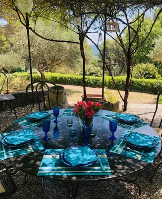 a table with blue napkins and glasses and flowers on it at Bastide de Bénezet in Mérindol