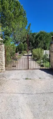 a gate to a park with trees and bushes at Appartement de la Villa Del Sol in Pierrevert