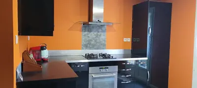 a kitchen with black cabinets and an orange wall at Appartement de la Villa Del Sol in Pierrevert