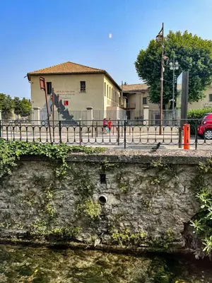 a stone wall next to a river with a building at Elivi Elegant Art Deco house with Garden Walk to the Heart of Town in LʼIsle-sur-la-Sorgue
