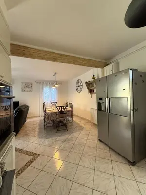 a kitchen with a table and a stainless steel refrigerator at Maison Tamaris in LʼIsle-sur-la-Sorgue