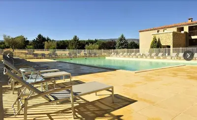 a swimming pool with lounge chairs next to a building at résidence avec piscines à proximité de Gordes in Gordes