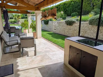 a patio with a table and chairs and a stone wall at Villa haut de gamme avec piscine et grand jardin in Aix-en-Provence