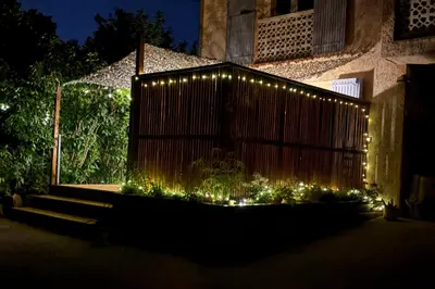 a fence with lights in front of a building at Logement avec jardin et terrain de pétanque privé in Venelles