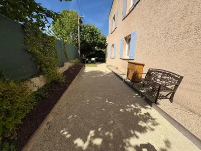 a bench sitting on a sidewalk next to a building at Logement avec jardin et terrain de pétanque privé in Venelles