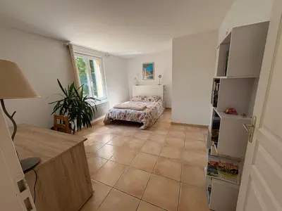 a living room with a bed and a tiled floor at Logement avec jardin et terrain de pétanque privé in Venelles