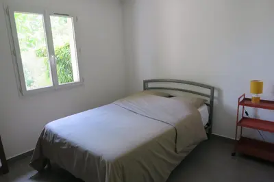 a white bedroom with a bed and a window at L'embellie in Châteaurenard