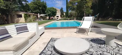 a patio with a white couch and a table and a pool at Mas Cabannes en Provence in Cabannes
