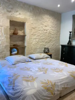 a bedroom with a bed with a stone wall at Maisonnette de charme 60m2 in Robion en Luberon