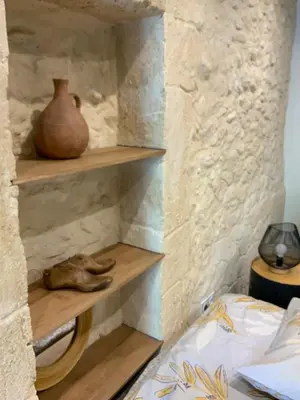 a room with wooden shelves in a stone wall at Maisonnette de charme 60m2 in Robion en Luberon