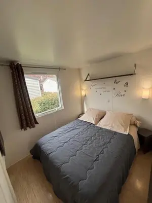 two beds in a small room with a window at mobil home AU SOLEIL in La Roque-dʼAnthéron