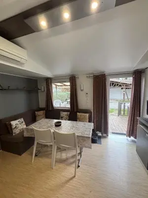 a dining room with a red couch and a table and chairs at mobil home AU SOLEIL in La Roque-dʼAnthéron