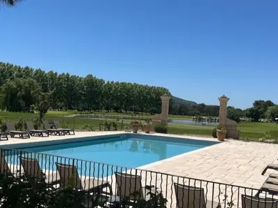 a large swimming pool with chairs and a fence at Appartement de charme sur le domaine de Pont Royal à Mallemort, en rez-de-jardin avec terrasse & piscine et vue sur le Golf in Mallemort